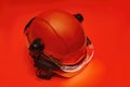 Protective goggles for eyes and construction helmet for head with earmuffs and headlamp on a red background. Construction tool and Royalty Free Stock Photo