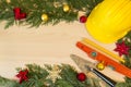 Protective helmet, mason tools and Christmas decorations on wooden background