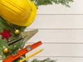 Protective helmet, mason tools and Christmas decorations on wooden white background