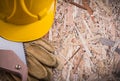 Protective leather gloves hard hat handsaw on chipboard Royalty Free Stock Photo