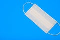 Protective medical disposable mask. White face mask, protection against viruses and bacteria, on a blue background, for quarantine Royalty Free Stock Photo