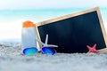 Protective sunscreen or sunblock and sunbath lotion in white plastic bottles with sandals on tropical beach. Closeup of a chalkbo