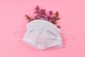 Protective white mask with lilac flowers on pink background. Royalty Free Stock Photo