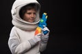 Pleasant kid cosmonaut is playing with toy gun