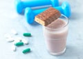 Protein bar, glass of protein shake with milk and raspberries. BCAA amino acids, L - Carnitine capsules and blue dumbbells in back Royalty Free Stock Photo
