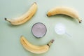 Protein powder and cocktail in a glass and banana on light green background. Healthy food. Top view, flat lay