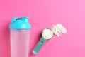 Protein powder, scoop and shaker on pink background, flat lay Royalty Free Stock Photo