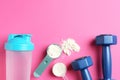 Protein powder, shaker and dumbbells on pink background, flat lay. Space for text Royalty Free Stock Photo