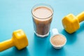 Protein shake in glass near dumbbells on blue background Royalty Free Stock Photo