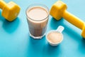 Protein shake in glass near dumbbells on blue background copy space Royalty Free Stock Photo