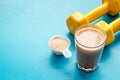 Protein shake in glass near dumbbells on blue background copy space Royalty Free Stock Photo