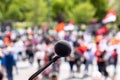 Protest, public demonstration or pension reform strike, focus on microphone, blurred crowd of people in the background Royalty Free Stock Photo