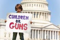 Protester holding sign children or guns in hands