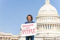 Protester holding sign migrants are people in hands