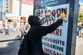 Protester wearing a black hoodie writes a slogan on an advertising sign board on the street with paint spray during Gezi park