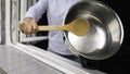 Protesting from the home against the government measures. Hitting cooking pan with wooden spoon