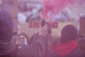 A protestor holds a smoke bomb at a political demonstration