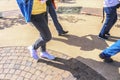 Protestors walk down city street - cropped with only legs and part of a sign showing