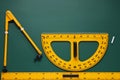 Protractor, compass, chalk and ruler on green chalkboard, flat lay