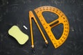Protractor, compass, chalk and sponge on blackboard, flat lay Royalty Free Stock Photo