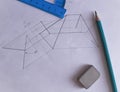 A protractor, pencil, and eraser lie on white paper with a drawn drawing.