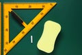 Protractor, sponge, chalk and ruler on green chalkboard, flat lay