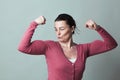 Proud beautiful 40s woman admiring her flexing muscles