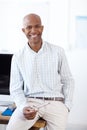 Proud of the company he built. Portrait of a smiling african american businessman sitting on a computer desk and smiling Royalty Free Stock Photo