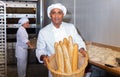 Hispanic baker showing fresh baked baguettes in bakery Royalty Free Stock Photo