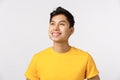 Proud and dreamy good-looking confident and cheerful asian man, wear yellow t-shirt, smiling delighted and contemplate