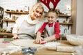 Proud entertained mother in striped apron controlling her daughter Royalty Free Stock Photo