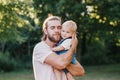 Proud father hugging embracing toddler baby boy outdoor. Young parent holding child son in arms. Authentic lifestyle tender moment