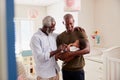 Proud Grandfather With Adult Son Cuddling Baby Grandson In Nursery At Home