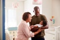 Proud Grandmother With Adult Son Cuddling Baby Grandson In Nursery At Home