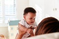 Proud Grandmother Cuddling Baby Grandson In Nursery At Home