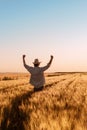 Proud happy victorious wheat farmer with hands raised in V