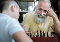 Joyful grandparent beaming while playing chess with kid Royalty Free Stock Photo