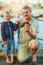 Proud of his boys first catch. Portrait of a father and his little boy fishing together at the harbor.