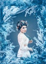 Proud majestic queen of winter and eternal cold in long white dress with dark collected hair adorned with frozen roses