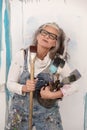 Proud older artist woman, in her fifties with grey hair and black glasses and many paintbrushes Royalty Free Stock Photo