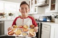 Proud pre-teen Hispanic boy standing in kitchen presenting the cakes heÃ¯Â¿Â½s made to camera, close up