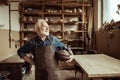 Proud senior potter in apron standing with ceramic bowl at workshop