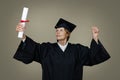 senior woman graduate in graduation gown and cap with college diploma