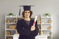 Proud college graduate standing in classroom, holding diploma and looking at camera Royalty Free Stock Photo