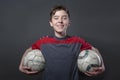 Proud, smiling teenage boy holding two soccer ball's