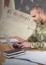 Proud soldier using a laptop with american flag background Royalty Free Stock Photo