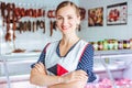 Proud woman selling meat and sausages in butcher shop