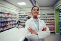 Proud young female with folded hands in labcoat standing in chemist near counter Royalty Free Stock Photo