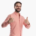 proud young man smiling while making thumbs up gesture with both hands Royalty Free Stock Photo