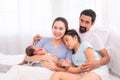 Proudly Asian man hug wife and 2 kids with love, care, protection, adorable daughter lie down on father`s bosom or chest looking Royalty Free Stock Photo